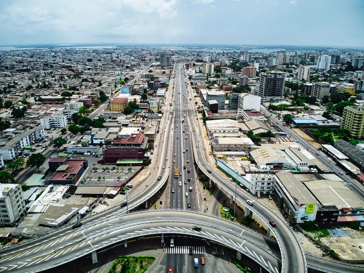 Vue aérienne d'Abidjan : dizaines de bâtiments tertiaires et commerciaux répartis de part et d'autre d'un axe.